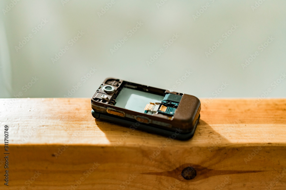 Old flip mobile phone without battery and cover. Broken. Plastic.  Technology. Design. Brown. Outmoded Stock Photo | Adobe Stock