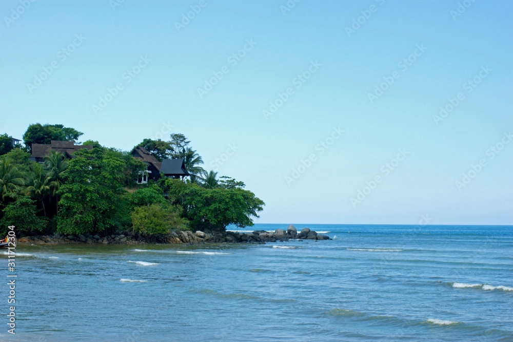 The coast of the Andaman Sea. Sand beach. Light waves roll ashore. A green cape and fishing boats in the background. A feeling of warmth and tranquility. The coast of the Andaman Sea. Sand beach. Light waves roll ashore. A green cape and fishing boats in the background. A feeling of warmth and tranquility.