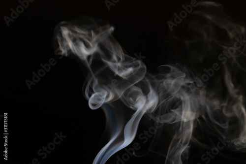 Abstract smoke background with copy space on black background. Blue-white smoke rose from the incense stick. Figures of smoke