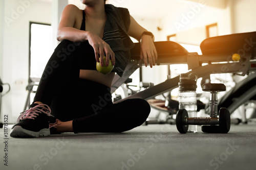 Woman holding apple after fitness exercise at gym. Healthy and lifestyle concept.