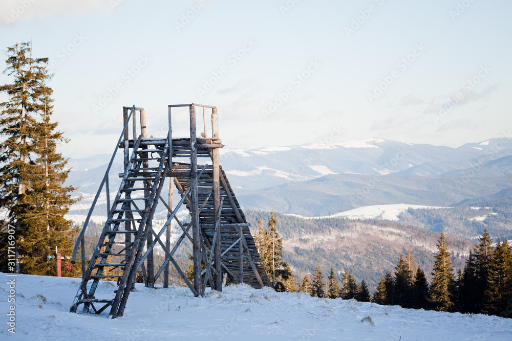 Landscape of sunset above coniferous winter forest and ski jump Landscape of sunset above coniferous winter forest and ski jump