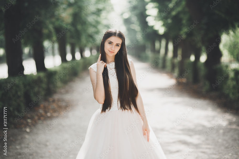Beautiful bride in elegant white dress holding bouquet posing in park Beautiful bride in elegant white dress holding bouquet posing in park