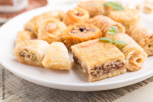 traditional arabic sweets (kunafa, baklava)  and a cup of coffee on a white wooden background. side view, selective focus.