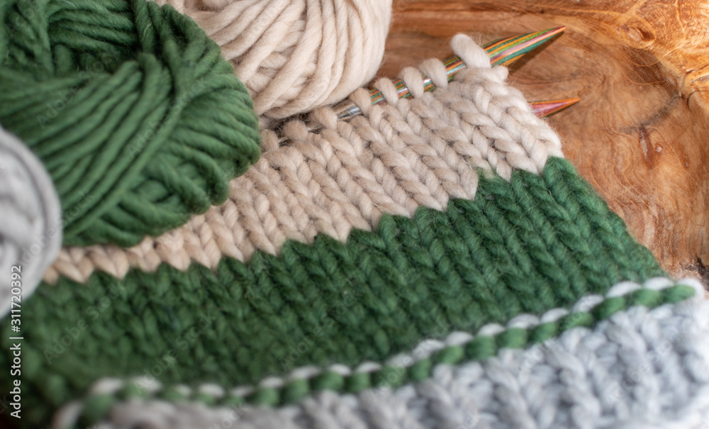 beige and green knitting on wooden needles 
