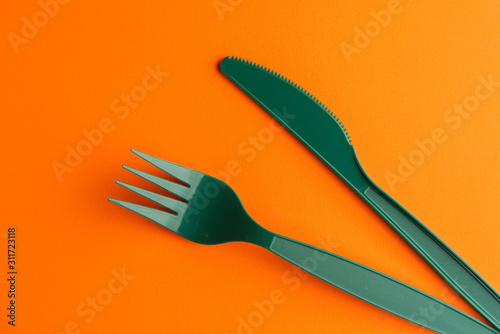 Plastic Fork And Knife On Orange Background  Green Plastic Fork And Knife