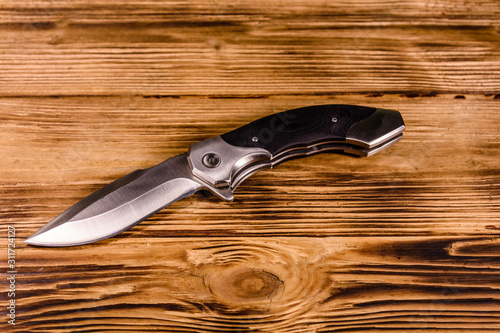 Opened folding knife on a wooden table