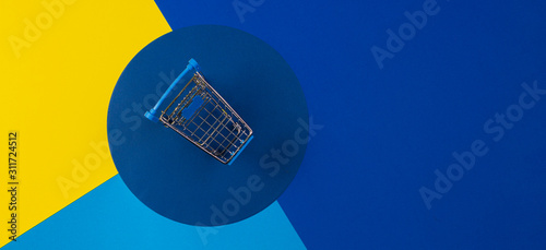 Mini shopping trolley cart on red yellow navy blue background. Online shopping, buy, sale, discount concept photo