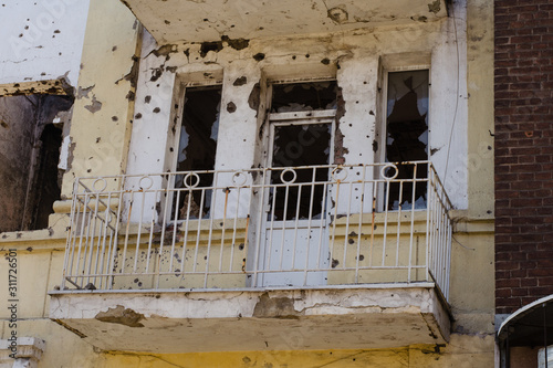Destroyed building after hostilities. Photo of the destroyed building, the theme of the war. Military actions. Wall with holes in several places. Crumbling wall of hostilities.