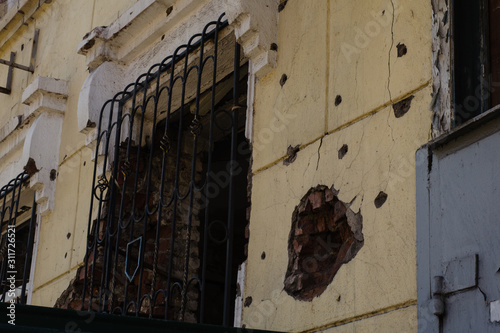 Destroyed building after hostilities. Photo of the destroyed building, the theme of the war. Military actions. Wall with holes in several places. Crumbling wall of hostilities.