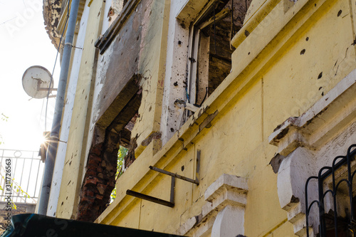 Destroyed building after hostilities. Photo of the destroyed building, the theme of the war. Military actions. Wall with holes in several places. Crumbling wall of hostilities.