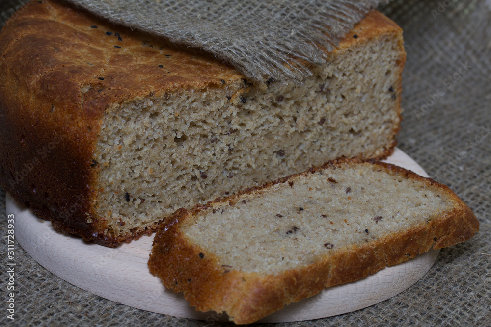 Freshly baked bread. A loaf of bread is cut and lies on a cutting board. The surface is covered with linen.