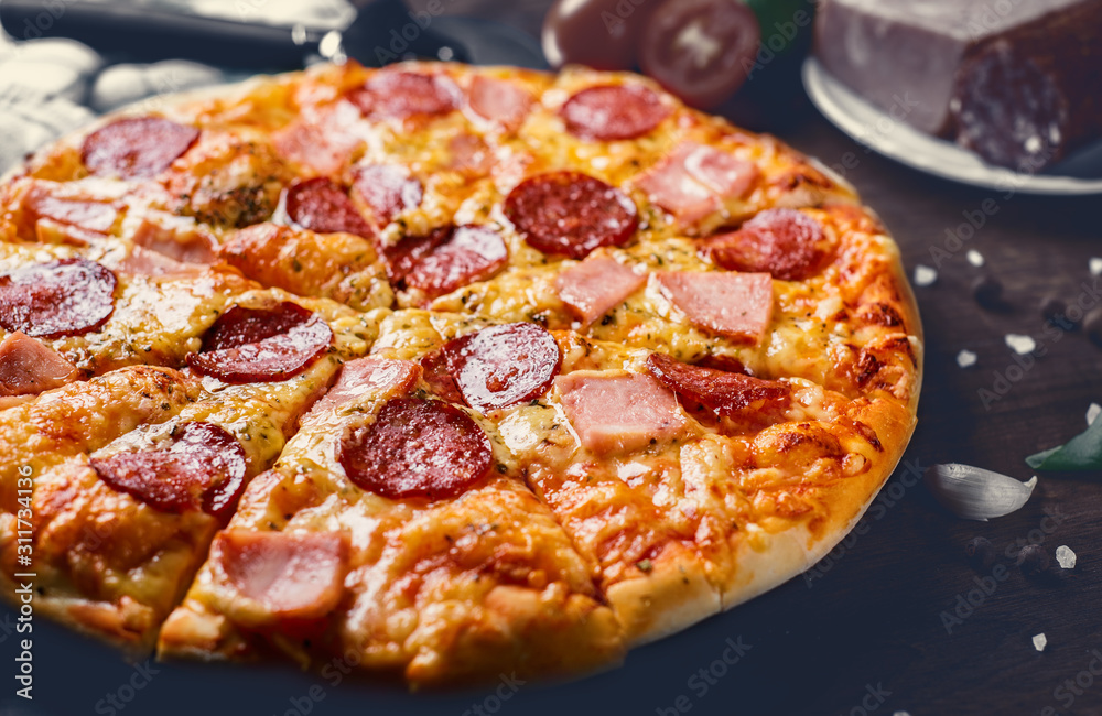 Pepperoni Pizza with Mozzarella cheese, salami, ham, Spices. Italian pizza on wooden table background
