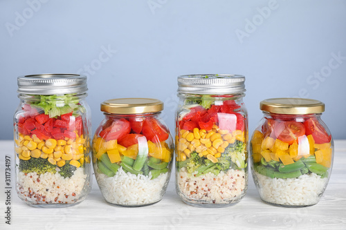 Glass jars with healthy meal on white wooden table