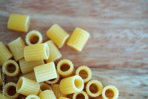 Close up view on traditional Italian pasta tubes on wooden background photo