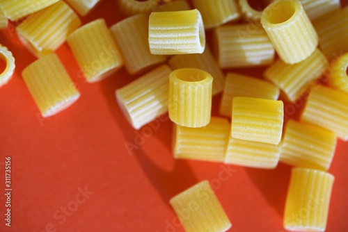 Macro view on uncooked traditional Italian pasta tubes ditaloni rigati on bright red background photo