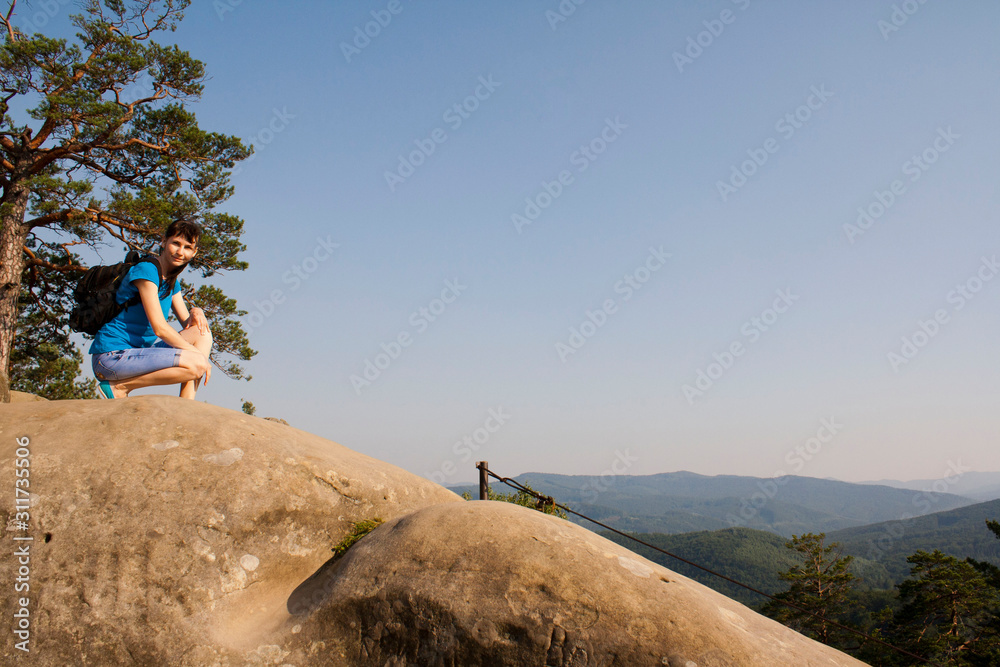 beautiful girl tourist with a backpack on a rock, mountains, rocks Dovbush, Ukraine