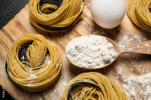 Raw linguine pasta and products on wooden board, flat lay