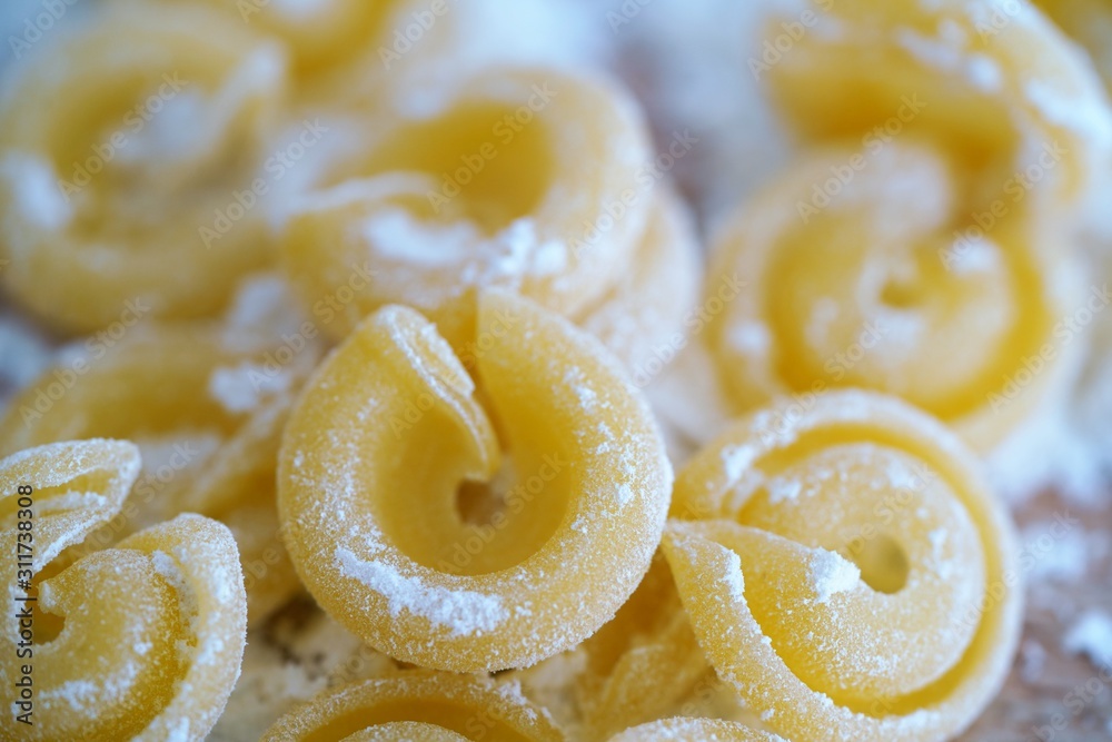 Top view on floury Italian pasta shapes on wooden background in white flour Top view on floury Italian pasta shapes on wooden background in white flour