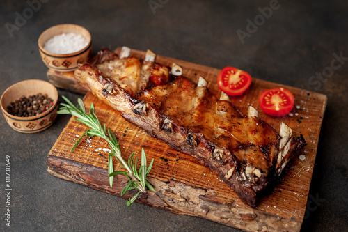 grilled pork ribs on a cutting board with spices on a stone background 