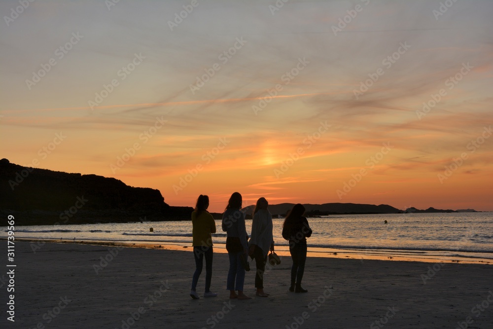 People in front of the sunset on the beach in brittany France People in front of the sunset on the beach in brittany France