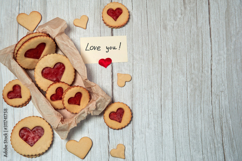 The Concept Of Valentine's Day. Homemade cakes for the holiday. A heart-shaped cookie box, a love note on a light wooden background.