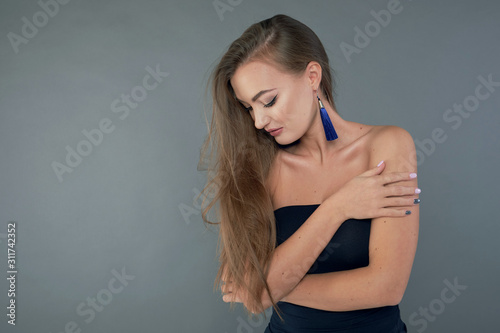 Woman with beauty long brown hair, posing at studio. long earrings classic blue