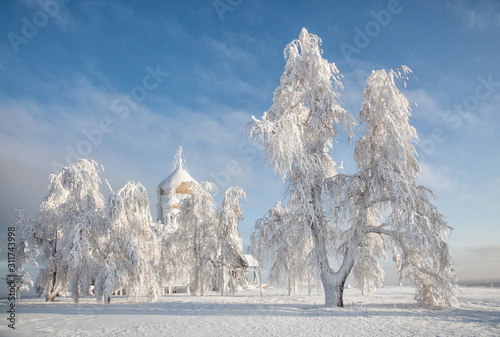 Belogorsky monastery in the Perm region on a frosty day, surrounded by snowy trees. photo