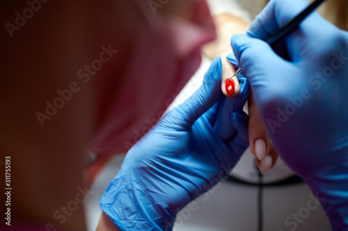 Young girl paints nails in red in a beauty salon