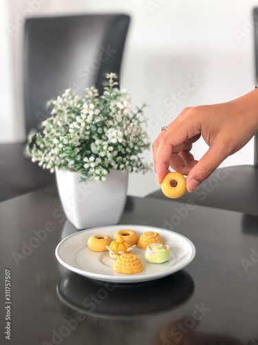 Women hand pick up a Thai auspicious desserts are consisting of Tong Ake, Ja Mong Gut and Sanay Chan. Decorated with white flower pots. Should eat less Because it can cause obesity. photo