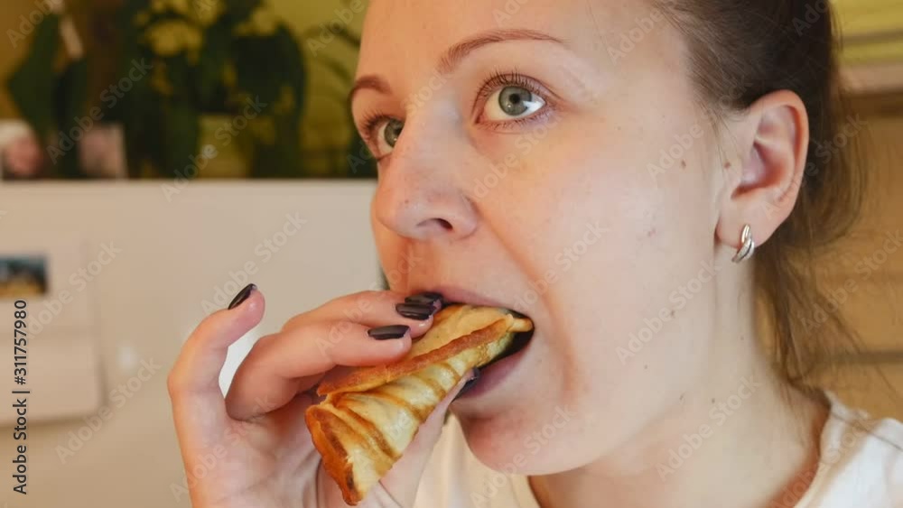 The woman in the kitchen takes the twisted pancake from the plate and tastes it. Close up shot The woman in the kitchen takes the twisted pancake from the plate and tastes it. Close up shot