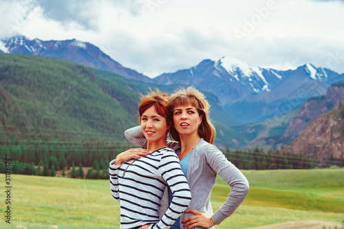 two girls stand against the mountains