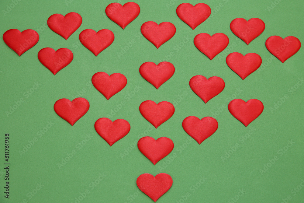red satin hearts on green background. Valentine's day card, pattern.