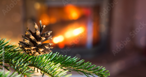 Christmas tree with fir tree cone against a stone fireplace.