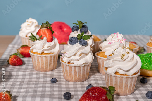 Candy bar. Cupcakes with blueberries strawberries and mint. Donuts in green and pink glaze with sprinkles. 