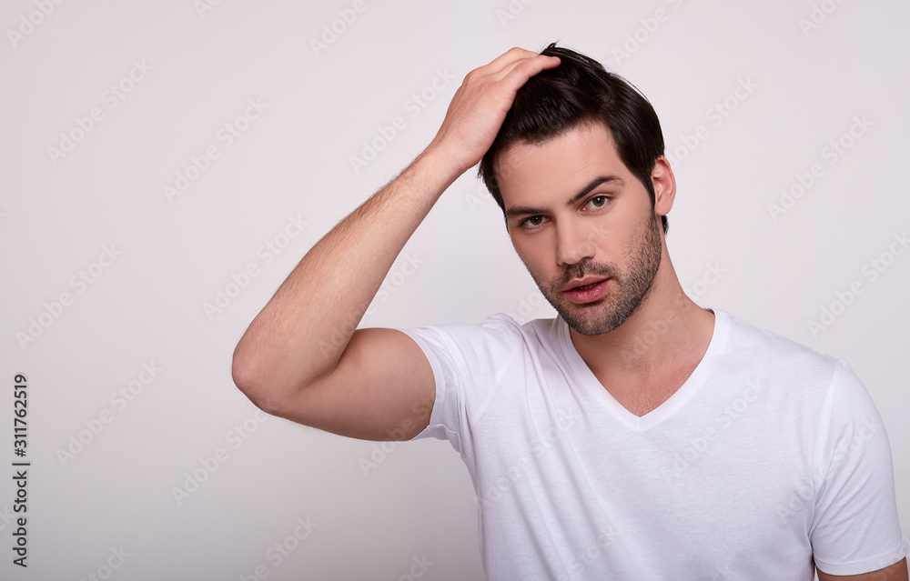 Sexy man sensually looks into the camera and touches his beautiful hair. Sexy man sensually looks into the camera and touches his beautiful hair.