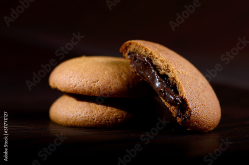 Biscuits filled with chocolate cream. Chocolate cream cookies. brown chocolate biscuits with cream filling on black background.