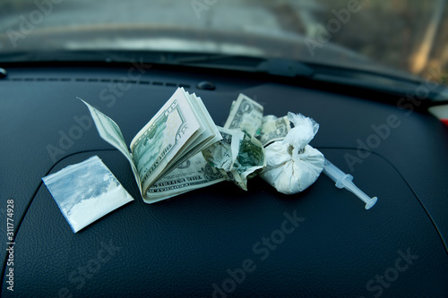 dope and bucks lie on the dashboard of the car