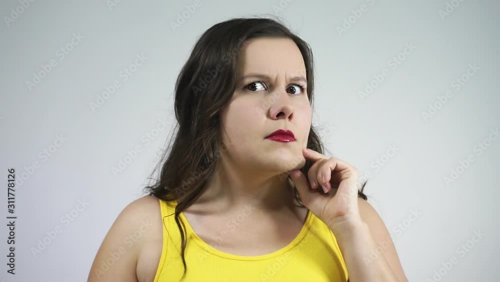 Young fat woman considers in the reflection his cheeks, double chin and crying Young fat woman considers in the reflection his cheeks, double chin and crying
