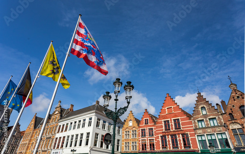Main city square in Bruges with flags and traditional architecture. Row of colorful building in Bruges.