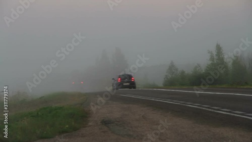 Extreme driving. Car with red taillights and red stoplight driving into the thick fog