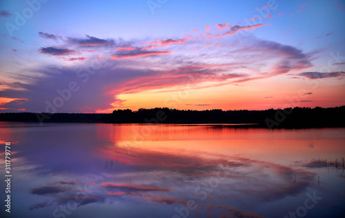 Sunset on the lake. A mirror image of lilac-pink clouds in the water.