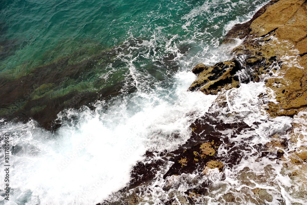 Turquoise sea surface and white sea foam and waves that splashes the stone on the coast Turquoise sea surface and white sea foam and waves that splashes the stone on the coast