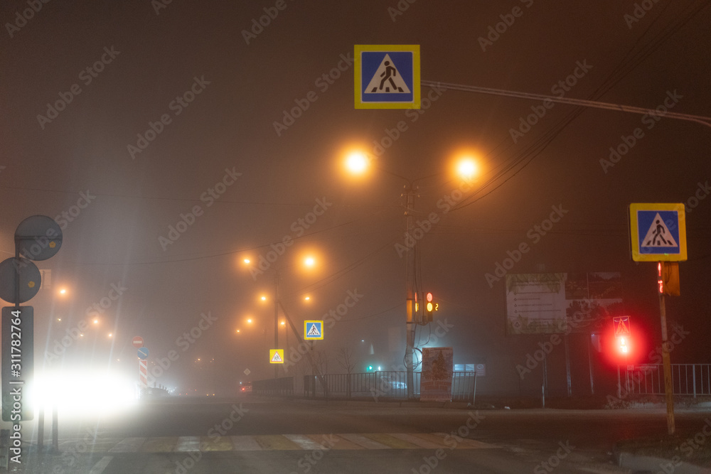 Fototapeta premium Traffic at an intersection in the fog