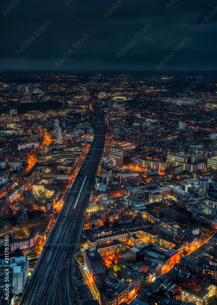 Aerial night view of east London, wide railway track with one train on it in middle