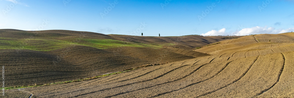Wide view over the green rolling hills of the Tuscan countryside in Italy. Wide banner.