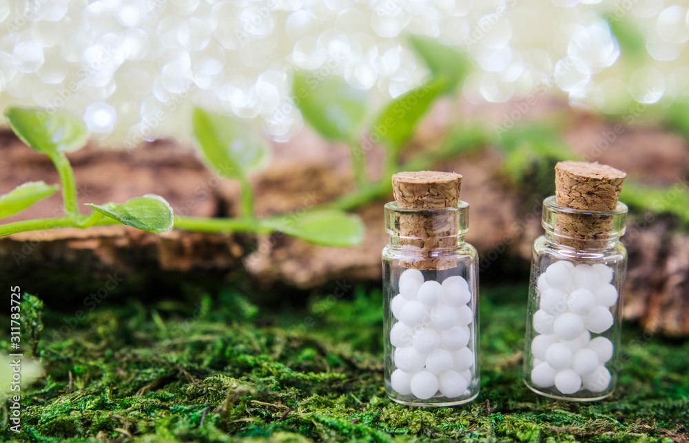 Homeopathic globule jelly beans in glass bottles close-up on a natural background. Selective focus. The concept of alternative medicine, banner, postcard. Copy space Homeopathic globule jelly beans in glass bottles close-up on a natural background. Selective focus. The concept of alternative medicine, banner, postcard. Copy space