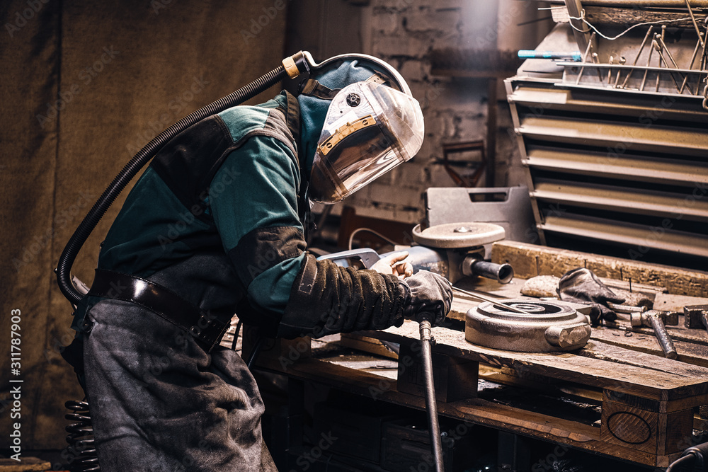 Experienced worker is repairing metal parts for machine tool at busy factory. Experienced worker is repairing metal parts for machine tool at busy factory.