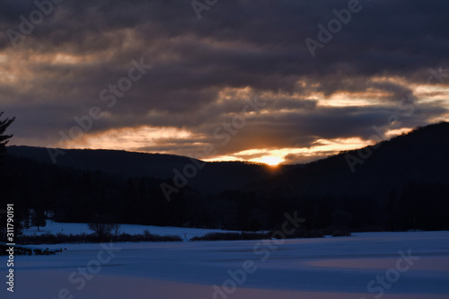 Cold Sunrise Over Tree Covered Hills And Frozen Water With Snow At Red House Lake  Allegany State Park  New York