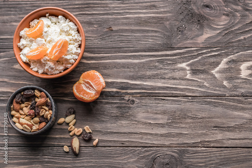 A set of products for a healthy balanced breakfast. Tangerines, nuts and cottage cheese, rich in vitamins and calcium on a wooden background. The concept of natural organic products in season.