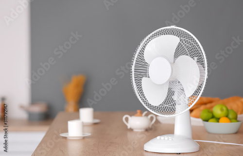Electric fan on table in kitchen photo